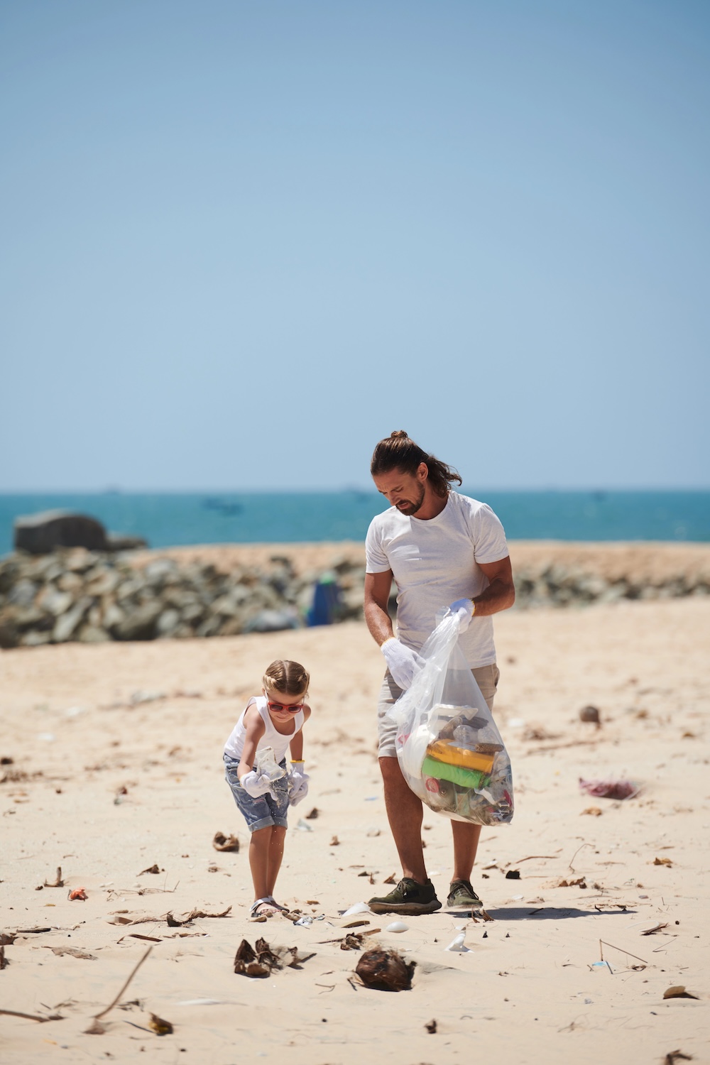 Father and child cleaning up a beach together, representing voluntourism values